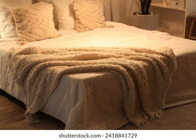 Soft blankets on comfortable bed and glowing lamps in cozy bedroom at night