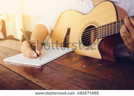soft and blur focus.song writer holding pencil compose a song.musician playing acoustic guitar.empty space for text.concept for live music festival.Instrument on stage,abstract musical background.