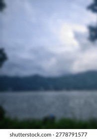 A soft blurred background featuring a tranquil lake surrounded by mountain ranges under a cloudy sky for artistic nature projects.