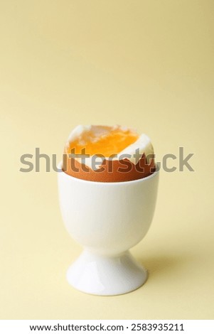 Soft boiled egg in eggcup on beige background, closeup