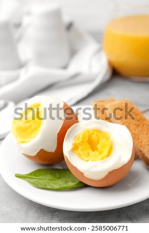 Soft boiled eggs with bread on grey table, closeup