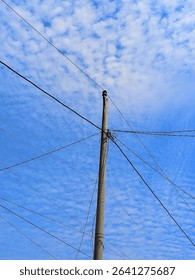 Soft clouds drift across a clear sky, framing a single pole in silent strength.

