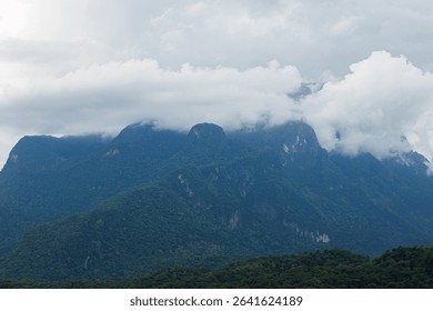Soft clouds drift over mountain peaks, revealing the serene and breathtaking beauty of untouched nature.