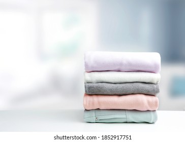 Soft Colors Stack Of Clothing,clothes Folded On Table Empty Copy Space Background.Colorful Garment Stacked.