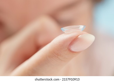 Soft contact lens on female finger against the blurred face, close up. Medicine and vision concept. Woman putting soft contact lens into eye. Shallow depth of field. - Shutterstock ID 2157910913