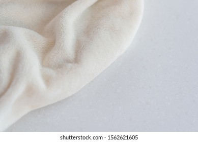 Soft cozy plush fabric with pile lies in beautiful folds on white marble countertop background. Copy space. Delicate mock up flat lay. 