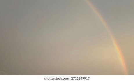 A soft, diffused sky features a single, clear rainbow segment. Muted gray, yellow, subtle pink tones dominate the frame, conveying a gentle, serene, atmospheric texture, symbolizing hope, transition.