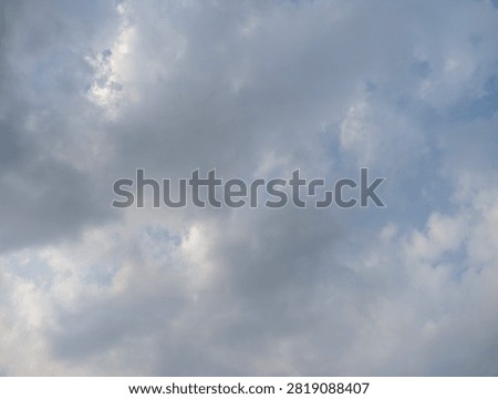 A soft, diffused sky filled with scattered white and grey clouds during a bright daylight afternoon.