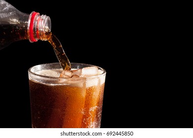 Soft Drink. Cola Being Pour Into The Glass On Black Background. Low Light Photo.