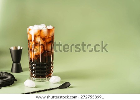 Soft drink Cola or cuba libre cocktail in a glass with ice cubes isolated on green background