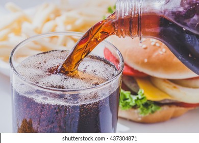 Soft drink pouring in a glass with hamburger on  white background