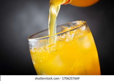 Soft Drink, Pouring Orange Soda Into Glass On Dark Background