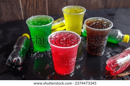 A lot of Soft drinks in colorful and flavorful glasses on the table, Glasses with sweet drinks with ice cubes Chilled on ice and flavorful on the black background, Soft drink or Carbonated beverages