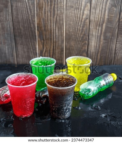 A lot of Soft drinks in colorful and flavorful glasses on the table, Glasses with sweet drinks with ice cubes Chilled on ice and flavorful on the black background, Soft drink or Carbonated beverage