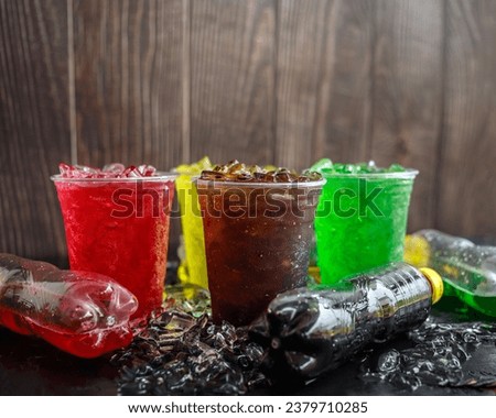 A lot of Soft drinks in colorful and flavorful glasses on the table, Glasses with sweet drinks with ice cubes Chilled on ice and flavorful on the black background, Soft drink or Carbonated beverage