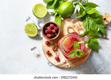 Soft drinks, healthy beverage. Refreshing summer glasses drink raspberry with mint lime and ice on a stone table. Top view flat lay background. Copy space.