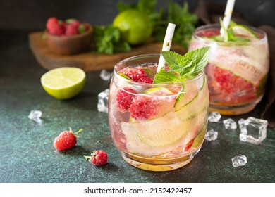 Soft drinks, healthy beverage, slimming water. Refreshing detox drinks made from organic raspberries, cucumbers, lime and mint leaves on a stone table.