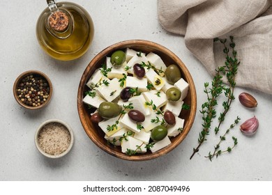 Soft feta cheese with olive oil, herbs and olives in wooden bowl on white background. Pieces of marinated cheese with fresh thyme - Powered by Shutterstock