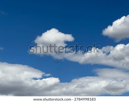 Soft fluffy white clouds floating across vivid blue sky in peaceful natural daytime atmospheric cloudscape