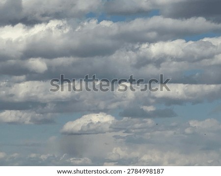 Soft fluffy white clouds floating across vivid blue sky in peaceful natural daytime atmospheric cloudscape