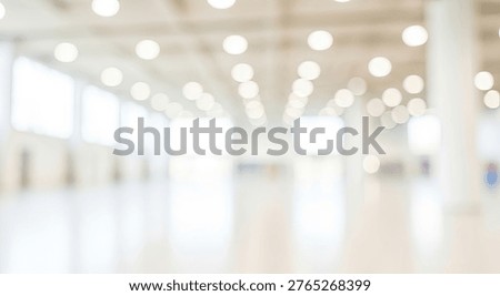 A soft focus, abstract background of a bright, clean interior space, possibly an office, hospital, or airport, featuring warm bokeh lights from overhead fixtures and a sense of spaciousness.
