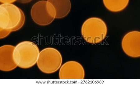 Soft focus abstract background featuring numerous glowing orange bokeh circles against a deep black background, creating a festive and warm atmosphere.