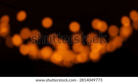 Soft focus abstract background with glowing orange bokeh lights creating a festive and magical atmosphere.
