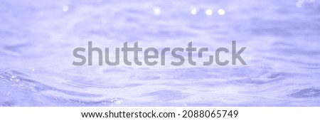 Soft focus abstract and blurred ocean or sea water with defocused bright sun light.Banner.Toned in color of the year 2022, very peri.