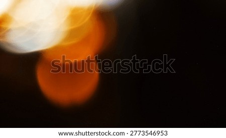 Soft focus abstract image featuring orange and white circular bokeh lights on a dark background