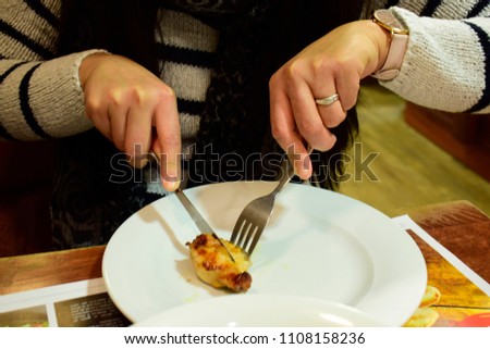 Soft focus of asian woman cut chicken spicy wing in white plate on the wood table in restaurant in vintage and grains style use for your pattern background. Food and lifestyle concept.