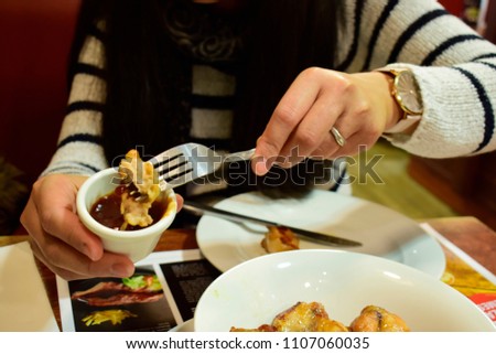 Soft focus of asian woman eat chicken spicy wing with tomato sauce in white plate on the wood table in restaurant in vintage and grains style use for pattern background. Food and lifestyle concept.
