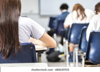 Soft Focus Focus Back View Examination Room With Undergraduate Or High School Students Inside. Student In Uniform Doing Final Exam Or Study In Lecture Room.