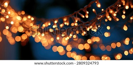 Soft focus background with numerous warm orange bokeh lights creating a festive and magical atmosphere against a deep blue backdrop.