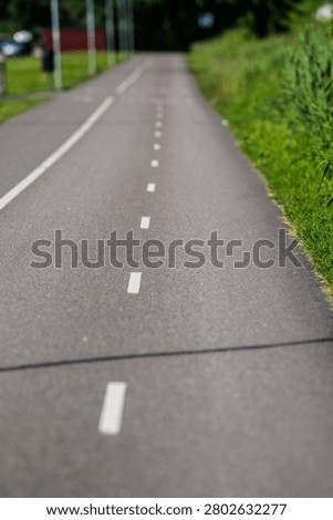 Soft focus bicycle path with green roadside grass and distance
