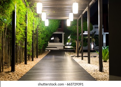 Soft Focus Of Black Wooden Garden Path Over White Pebbles Floor And Palm Trees On Side At Night, Garden Decoration.