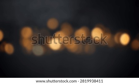 Soft focus bokeh lights create a warm and inviting abstract background with glowing orange and yellow circles on a dark background.