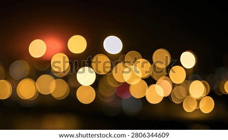 Soft focus bokeh lights in warm golden and yellow tones against a dark background, creating a dreamy and atmospheric effect.