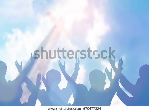 soft focus of christian people group raise\
hands up worship God Jesus Christ together in church revival\
meeting with image of wooden cross over cloudy sky can be used for\
Christian worship\
background