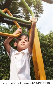 Soft Focus And Close Up The Asian Kid 4 Year Old Using Two Hand Holding Monkey Bar To Lift Up In The Air. The Asia Boy Play In The Playground. Concept Happy Kids, Activity And Safety Exercise.