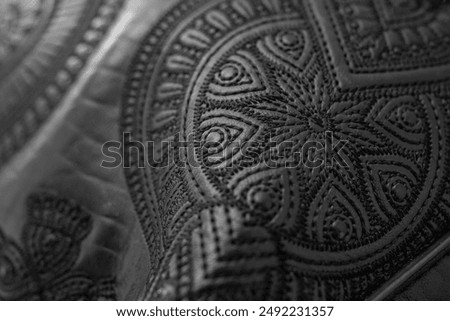 Soft focus close up detail of  thread embroidery floral design on black genuine leather, abstract textured detail backdrop 