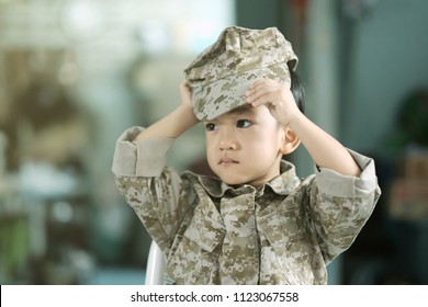 Soft focus and closeup at Asian kid wearing soldier suit and try to wearing a hat.  The handsome boy wear military uniform / concept of dream, future, culture and indoctrination. - Shutterstock ID 1123067558