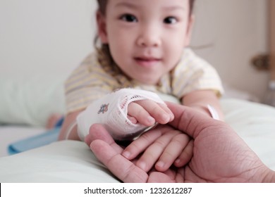Soft focus and Closeup the parent hand holding two hands of patient Asian kid. Patient kid smile and look at camera. The bandage cover on baby hand. Concept support, get well soon, recovery, Take care