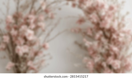 A soft focus, close-up view of a beautiful wreath made of pink cherry blossoms and natural twigs, set against a clean white backdrop.