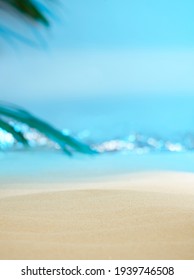 Soft focus, dreamy, sandy beach with palm tree leaf and sparkling waves