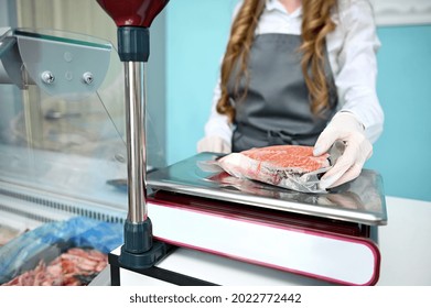 Soft focus fishmonger hand weighing a salmon steak fillet on a scale. Seafood retail Seafood retail