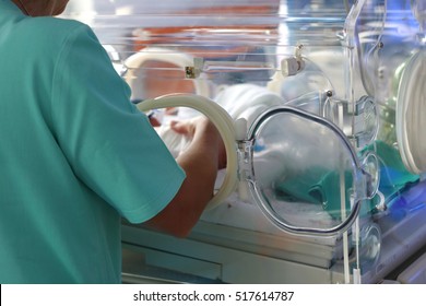 Soft focus Hand of a nurse or doctor checking a baby in the incubator