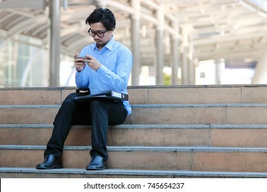 Soft focus of handsome young Asian business man in blue shirt looking mobile smart phone at outside office - Shutterstock ID 745654237