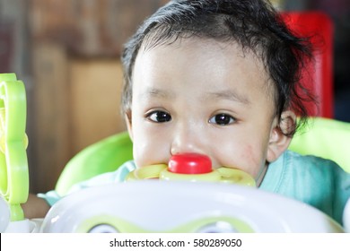 Soft focus image of cute smiling baby girl looking towards camera with toy walker in the wooden house.