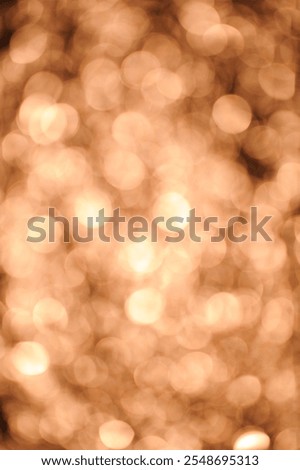 A soft focus image features a multitude of out-of-focus circular lights in warm, amber tones. The effect creates a dreamlike, hazy quality reminiscent of a golden sunset reflected on water.