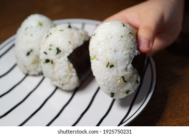 Soft Focus Image Of A Kid's Hand Holding A Japanese Rice Ball 